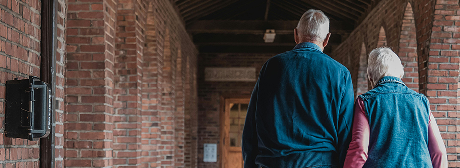 Two people walk down a brick hallway together